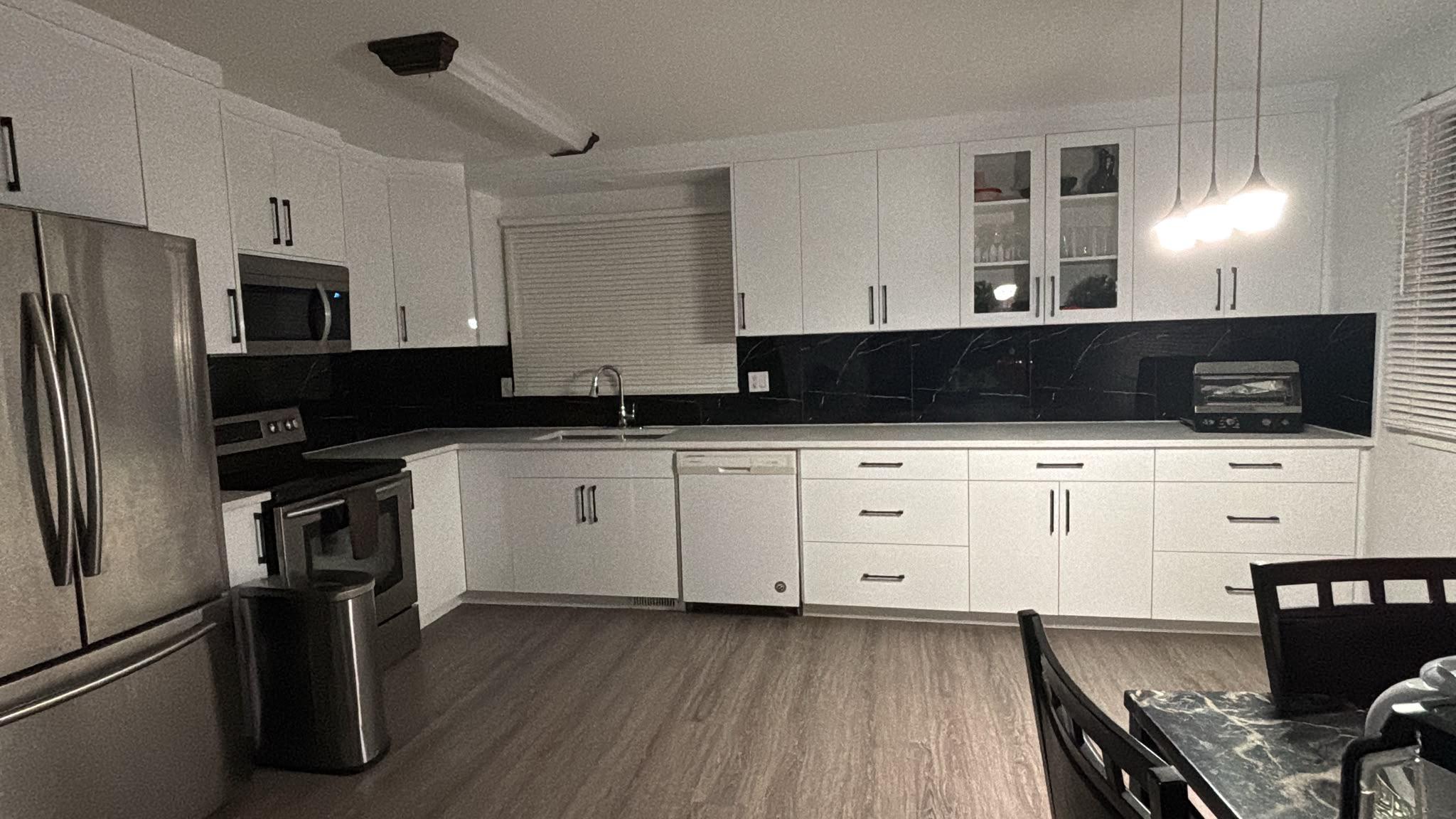 White kitchen with black backsplash and new flooring